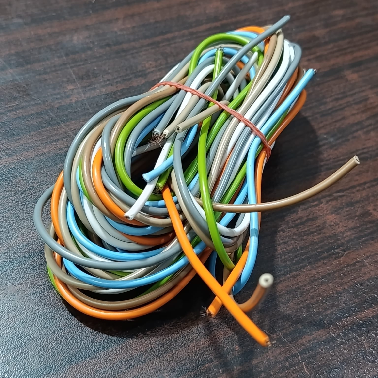 1 Meter 7 Core Wiring Cable - shown as a coiled bundle of multi-coloured insulated wires secured with a rubber band on a dark wooden surface.