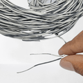 1 Meter Hard Jumper Wires Spiral Wrap Wires Cable - shown as a coiled bundle of black and white wires with a hand holding two stripped wire ends.