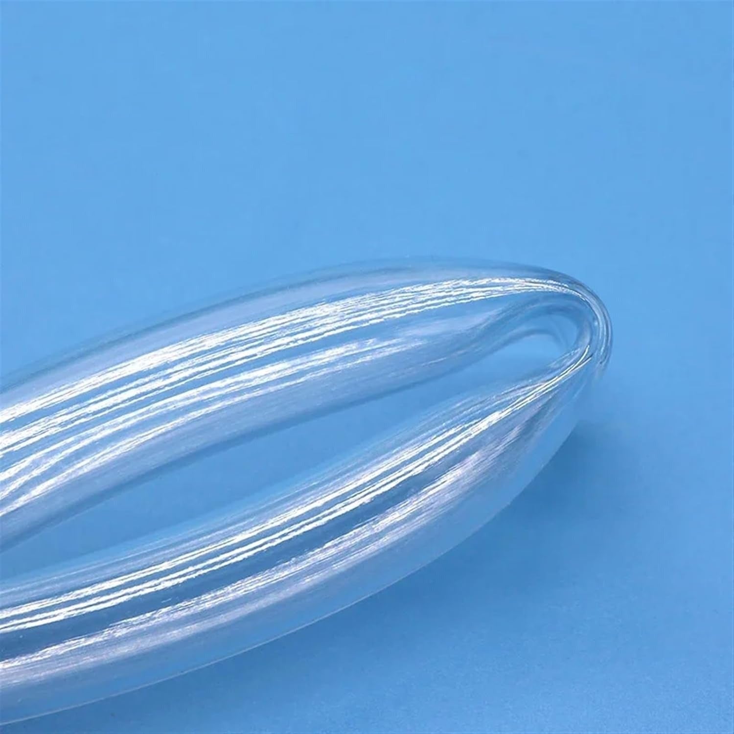 1 Meter Tube Size 6x4 mm | Flexible PVC Tube For Plumbing &amp; Electrical Applications - a close-up view of a clear, flexible PVC tube curved into a loop against a solid blue background.