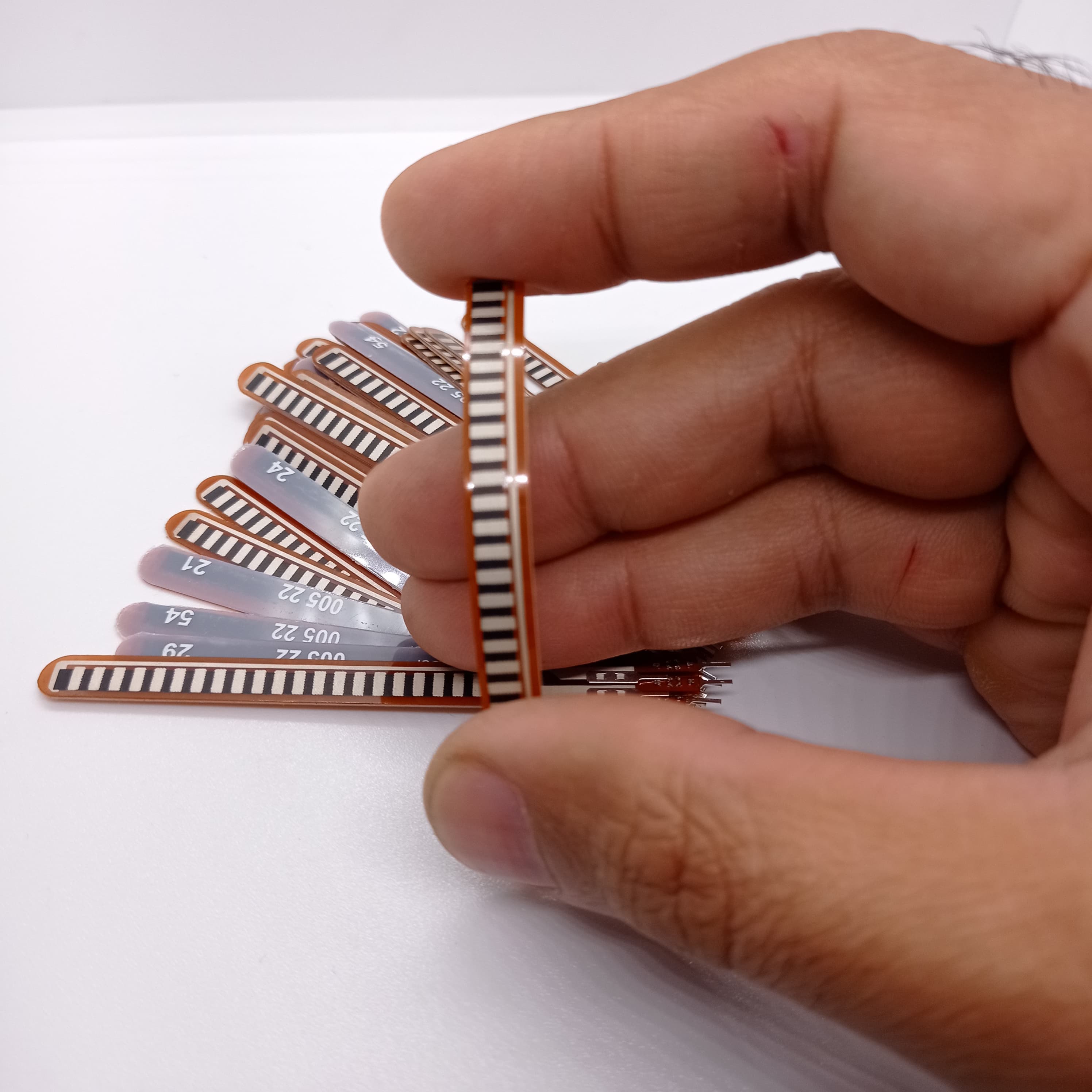 1 Piece 2.2 Inch Flex Sensor Bend Detection Sensor - a thin, brown, rectangular strip with a series of black parallel conductive lines.