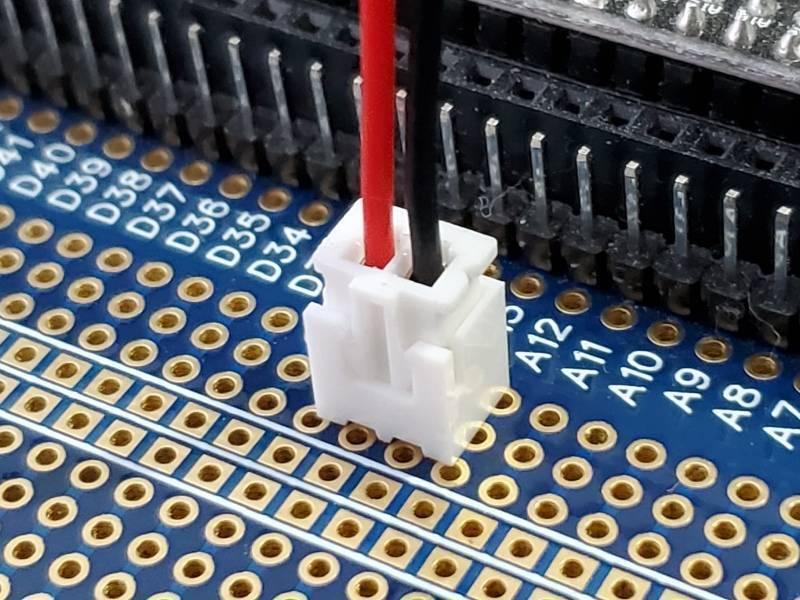 1 Piece 2.54mm Pitch JST2.54 Plug 2 Pin Extension Wire Connector - shown as a white plastic two-pin connector with red and black wires plugged into a blue circuit board.
