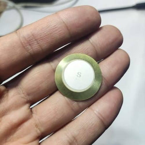 1 Piece 27mm Piezoelectric Transducers Piezoelectric Sensor , Piezo Transducer - a close-up of a circular brass-rimmed sensor with a white center held in a hand.