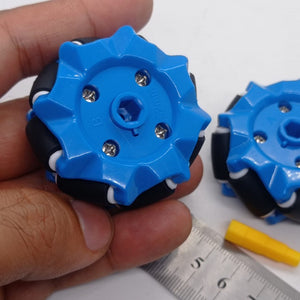 1 Piece 52mm Mecanum Omni Wheels Tires For DIY Rc Robot Toys Tt Motors - two blue wheels with black rollers held by a hand next to a metal ruler and a yellow hexagonal axle connector.