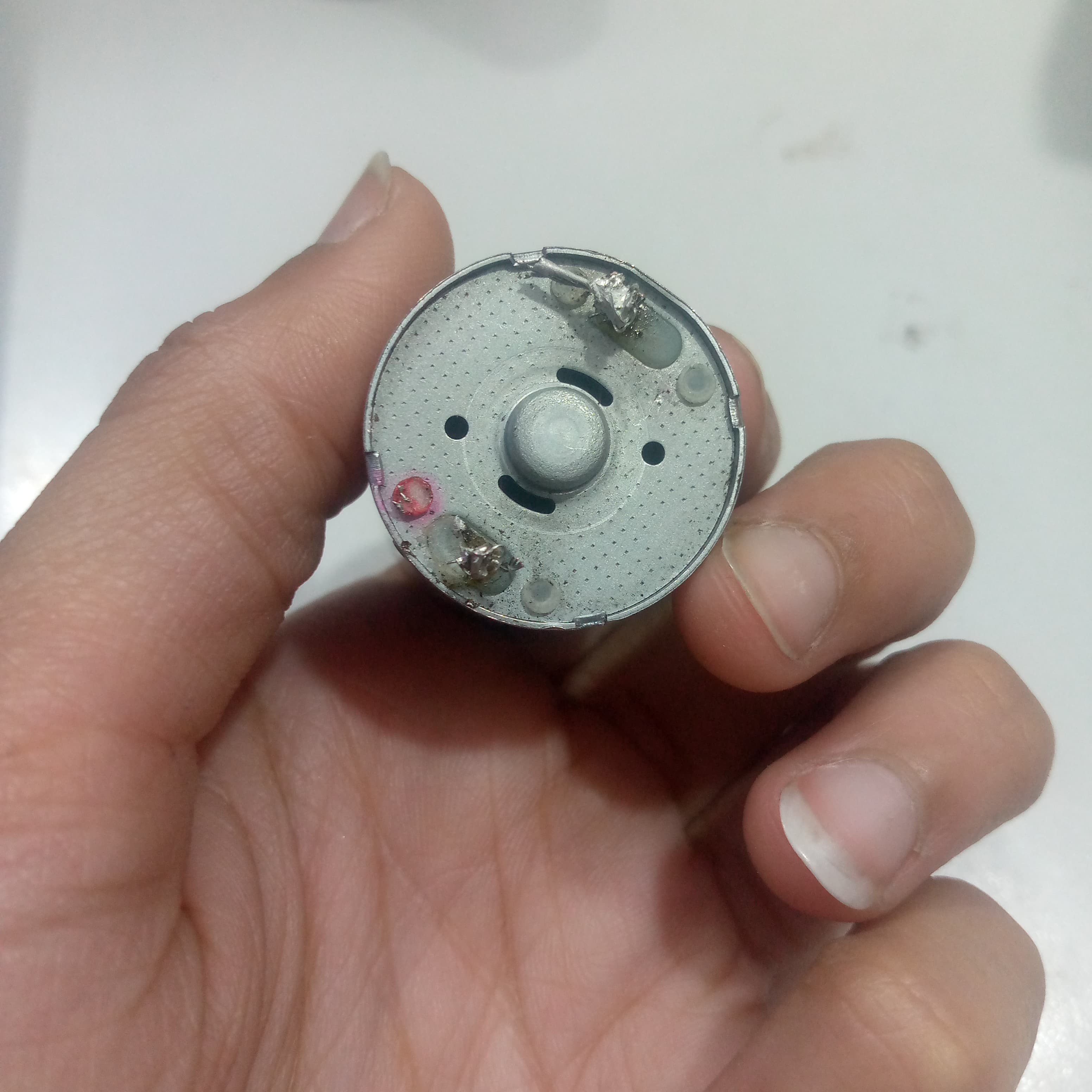 1 Piece DC 2V To 24V 8960RPM High Torque Mini Micro Motor DC Motor - a close-up view of the circular rear end showing two soldered metal terminals held in a hand.