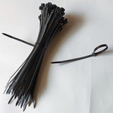 100 Pcs Black Color 6 Inch Cable Tie Zip Ties - shown as a large bundled stack of black plastic ties with one single tie looped and fastened.
