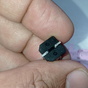 1000uF 16V SMD Capacitor D10XL10.2mm Aluminum Electrolytic Capacitors - SMD - a close-up view of the black base with two metal pins held between fingers.