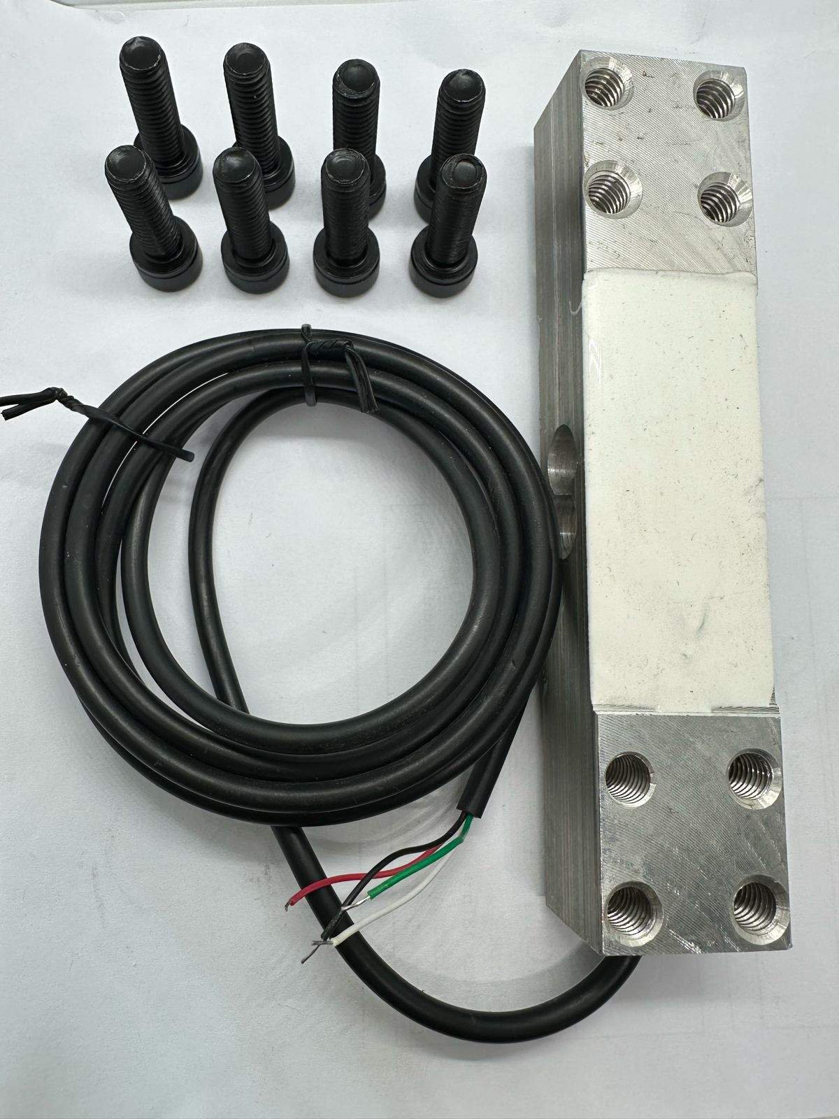 100kg Capacity Load Cell - shown with a black cable and eight black mounting bolts arranged on a white surface.