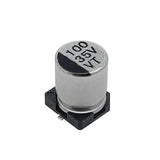 100uF 35V Vt SMD Capacitor | High-quality Surface Mount Capacitor | Digilog.pk - a silver cylindrical surface-mount electrolytic capacitor with a black base and markings reading 100, 35V, and VT.