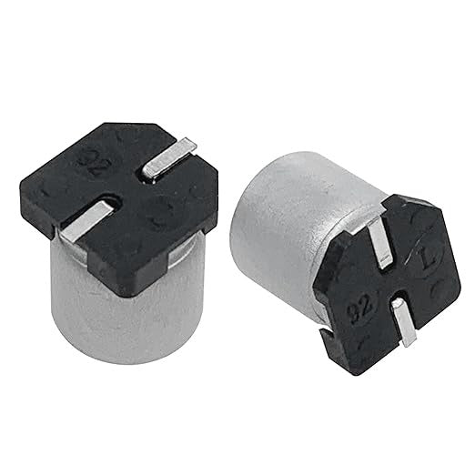 100uF 35V Vt SMD Capacitor | High-quality Surface Mount Capacitor | Digilog.pk - two cylindrical silver surface-mount capacitors with black plastic bases and two metal pins each.