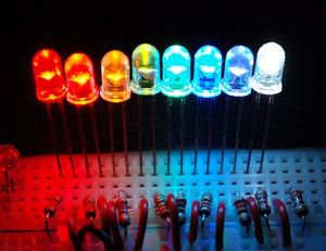 10mm Green LED Light Emitting Diode - shown in a row of eight multi-coloured LEDs glowing on a breadboard with connected resistors.