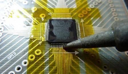 10mm Kapton Polyimide Heat Resistant Tape - applied to a circuit board around a microchip while a soldering iron tip touches the pins.