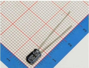 10uF 25V Electrolytic Capacitor - a small black cylindrical electronic component with two metal leads, placed on a grid-patterned surface.