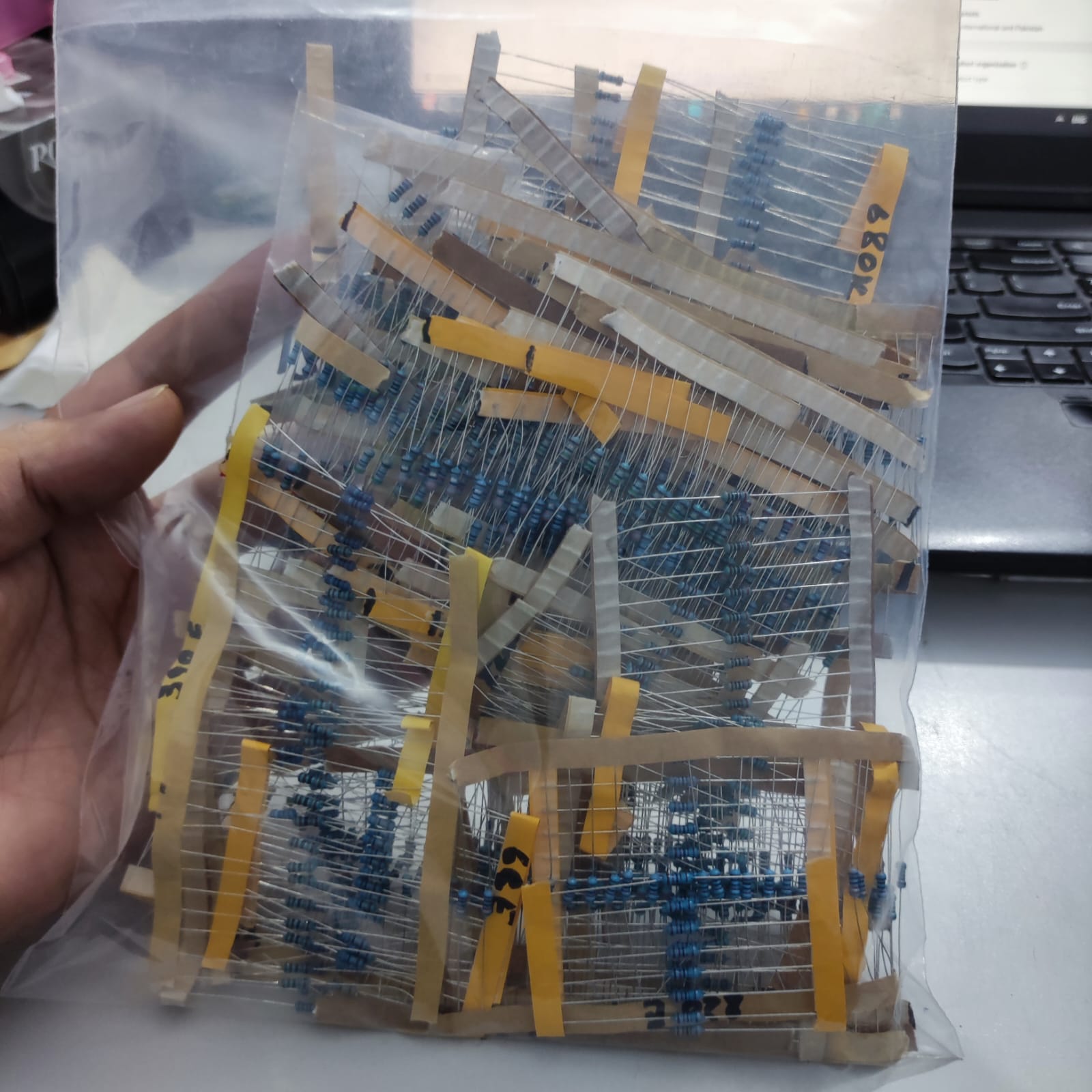 1100pcs Of Different Values 1% Resistors 20pcs Each Value - shown in a clear plastic bag containing multiple strips of blue axial resistors with tape.
