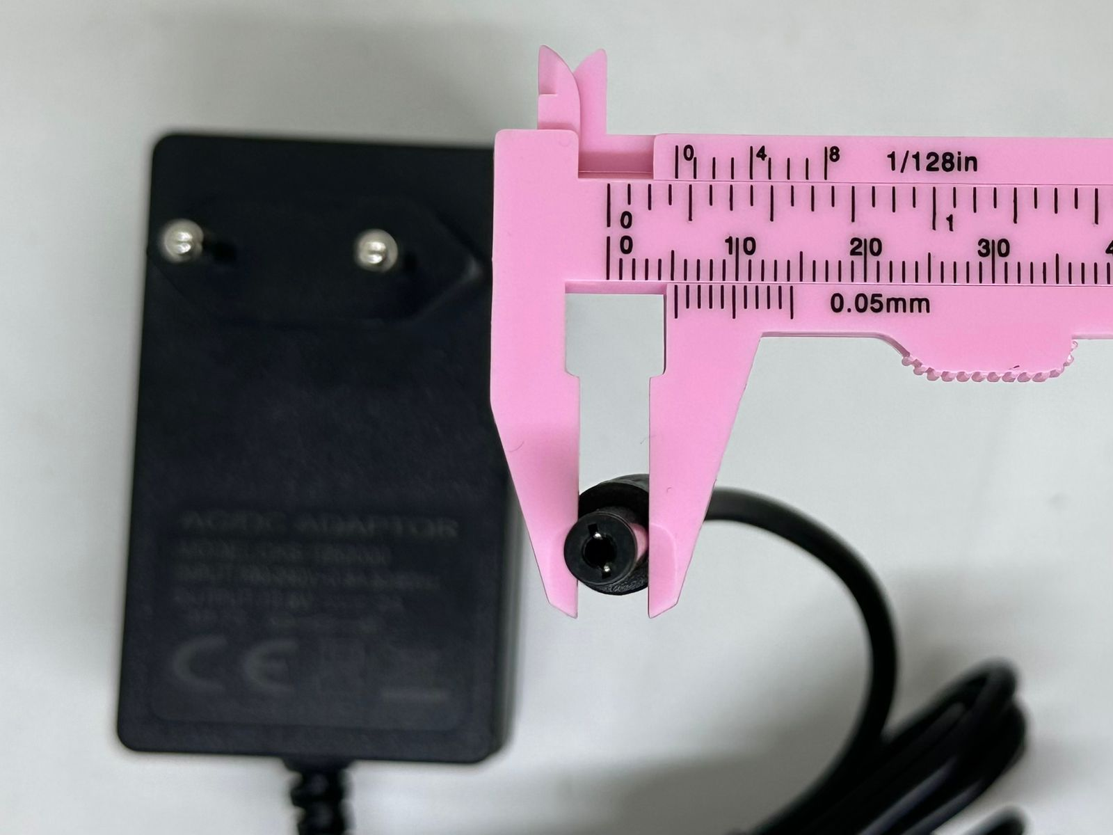 12.6V 2A DC Power Adapter – Eu Plug With Barrel Jack - shown with a pink plastic caliper measuring the outer diameter of the black barrel connector.