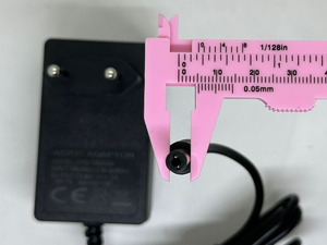12.6V 2A DC Power Adapter – Eu Plug With Barrel Jack - shown with a pink plastic caliper measuring the outer diameter of the black barrel connector.