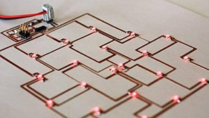 12mm One Sided Copper Foil Conductive Adhesive Tape - applied as conductive traces on a white surface, connecting a small circuit board to several red LEDs.