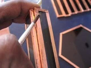 12mm One Sided Copper Foil Conductive Adhesive Tape - shown in a close-up as a person uses a brush to apply flux to the copper-edged glass panels.