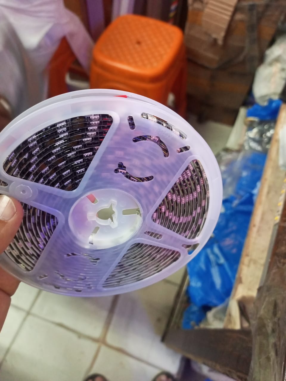 12V DC 5 Meter Warm LED Strip - coiled on a clear plastic spool held in a hand.