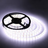 12V DC 5 Meter White LED Strip - shown coiled on a black plastic spool, illuminated with a bright white light against a dark background.