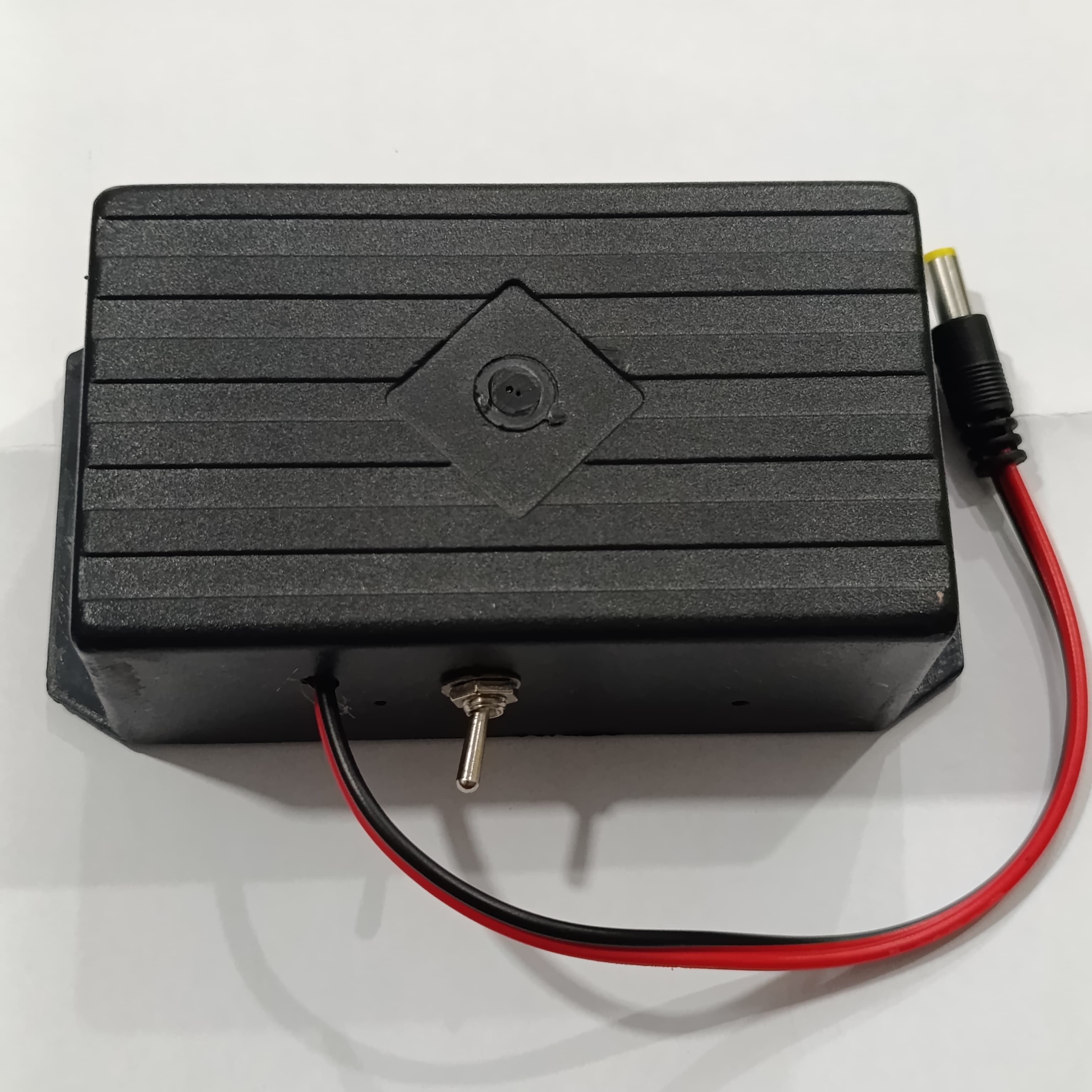 12V WiFi Router Power Bank Without Adapter - a black rectangular plastic enclosure featuring a central toggle switch and a red and black DC power cable.