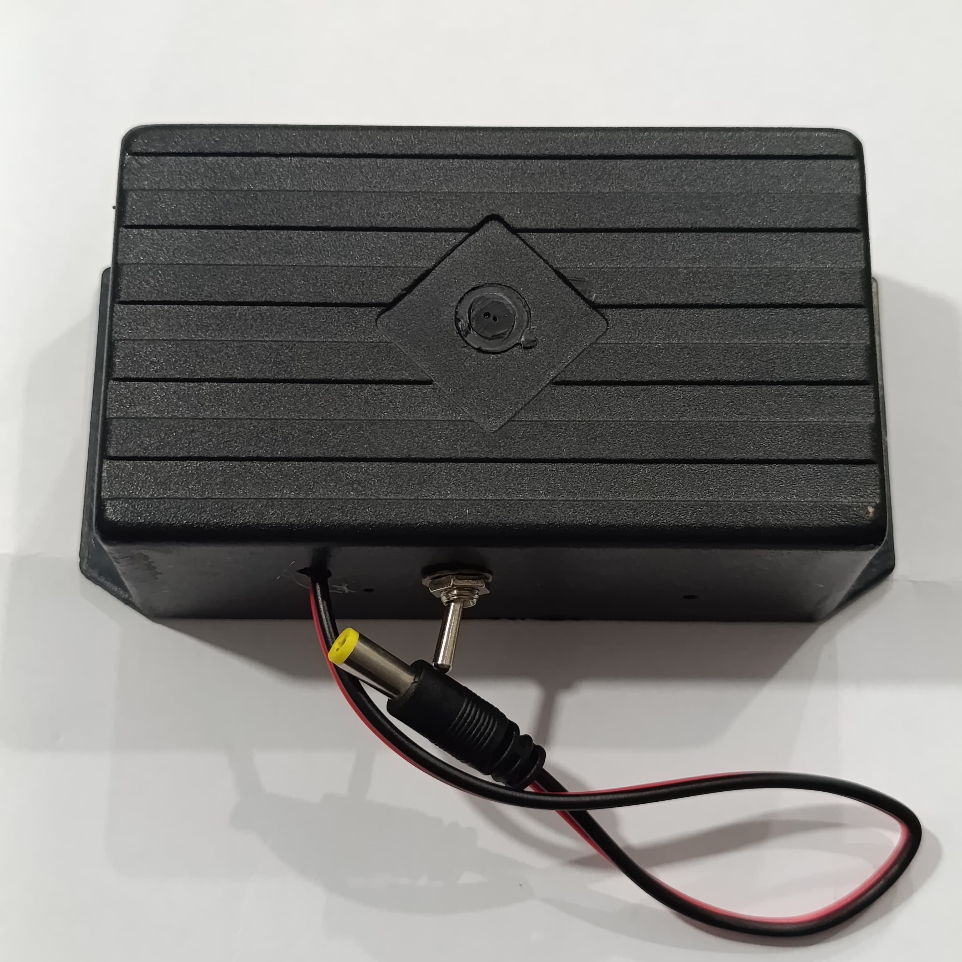 12V WiFi Router Power Bank Without Adapter - a black rectangular enclosure featuring a top-mounted circular port, a toggle switch, and a DC power cable.