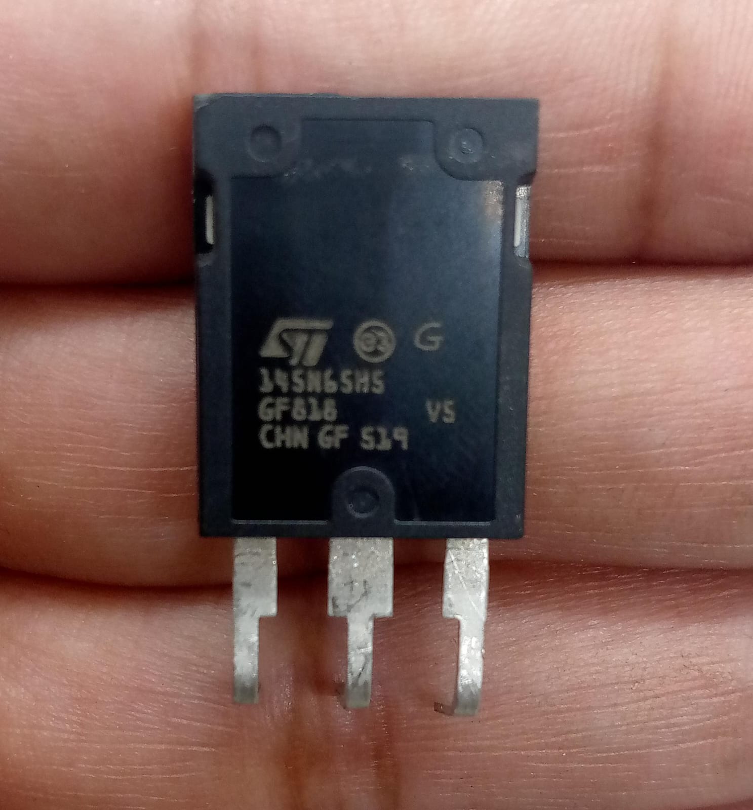 145A 650V MOSFET 145N65HS GF818 Chn - High-efficiency Power Transistor - a black rectangular electronic component with three metal pins, held between fingers, showing the printed text on its front surface.
