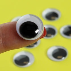 15mm Googly Eyes 12pcs - a close-up of a single round plastic googly eye with a black pupil held on a finger against a yellow background.