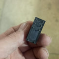 16A 250VAC 24V 8 Pin Relay - a close-up showing the black rectangular base of the component with eight metal connector pins held in a hand.