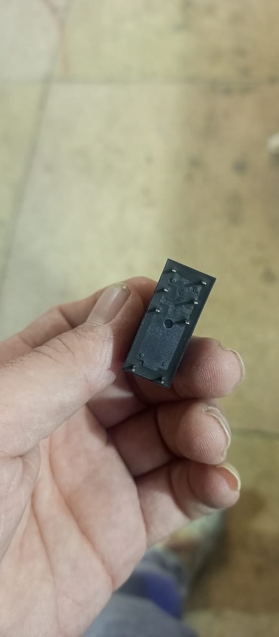 16A 250VAC 24V 8 Pin Relay - a close-up showing the black rectangular base of the component with eight metal connector pins held in a hand.