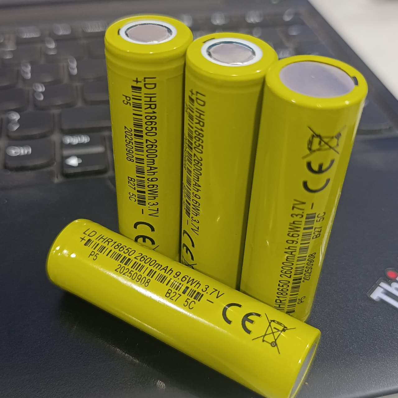 18650 1600mAh 3.7V Li-ion Rechargeable Cell For DIY Projects - four yellow cylindrical batteries with printed technical specifications resting on a laptop keyboard.