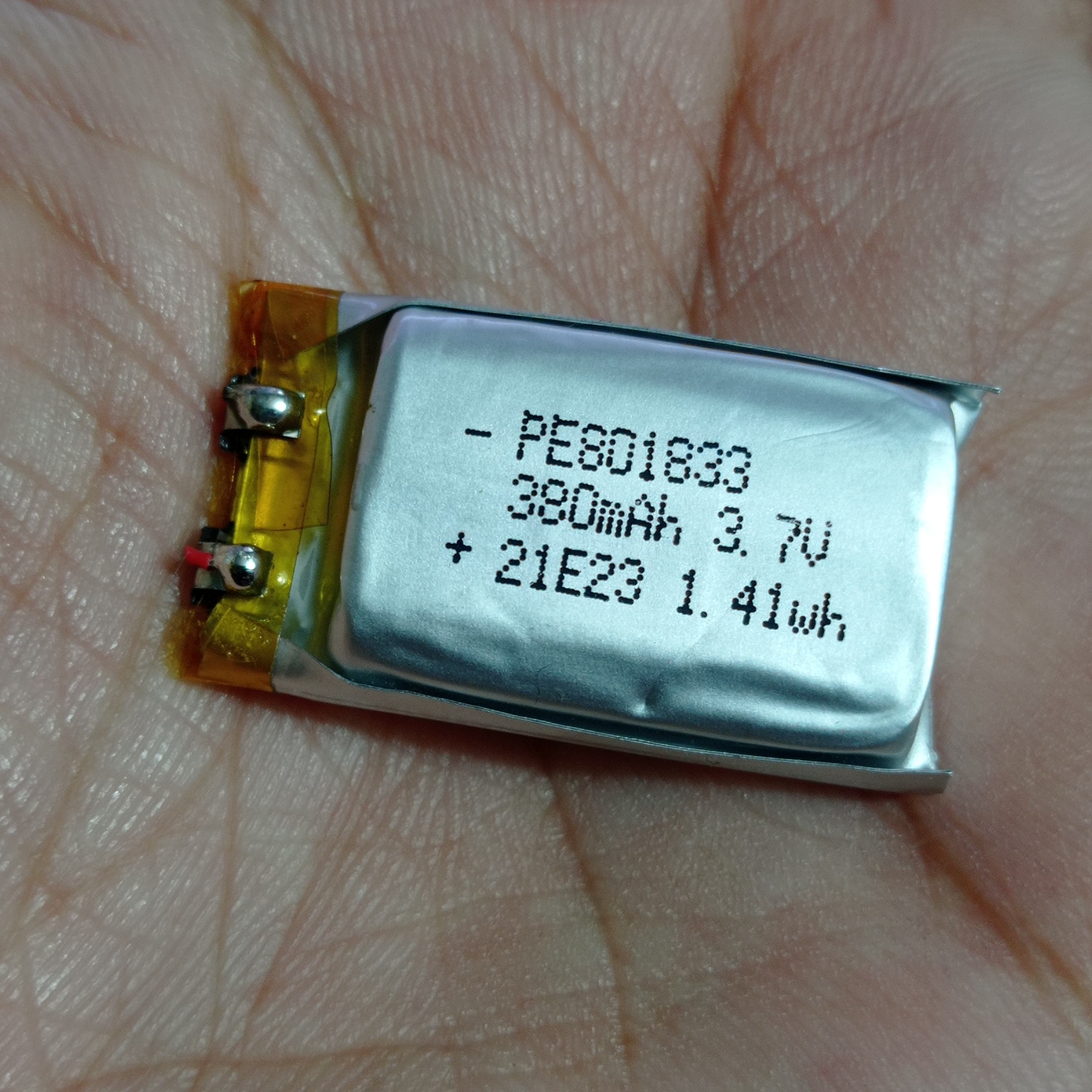 18mm x 33mm x 8mm 3.7V 380mAh Li Ion Battery - a small rectangular silver lithium-ion cell held in a palm, showing printed specifications and two wires.