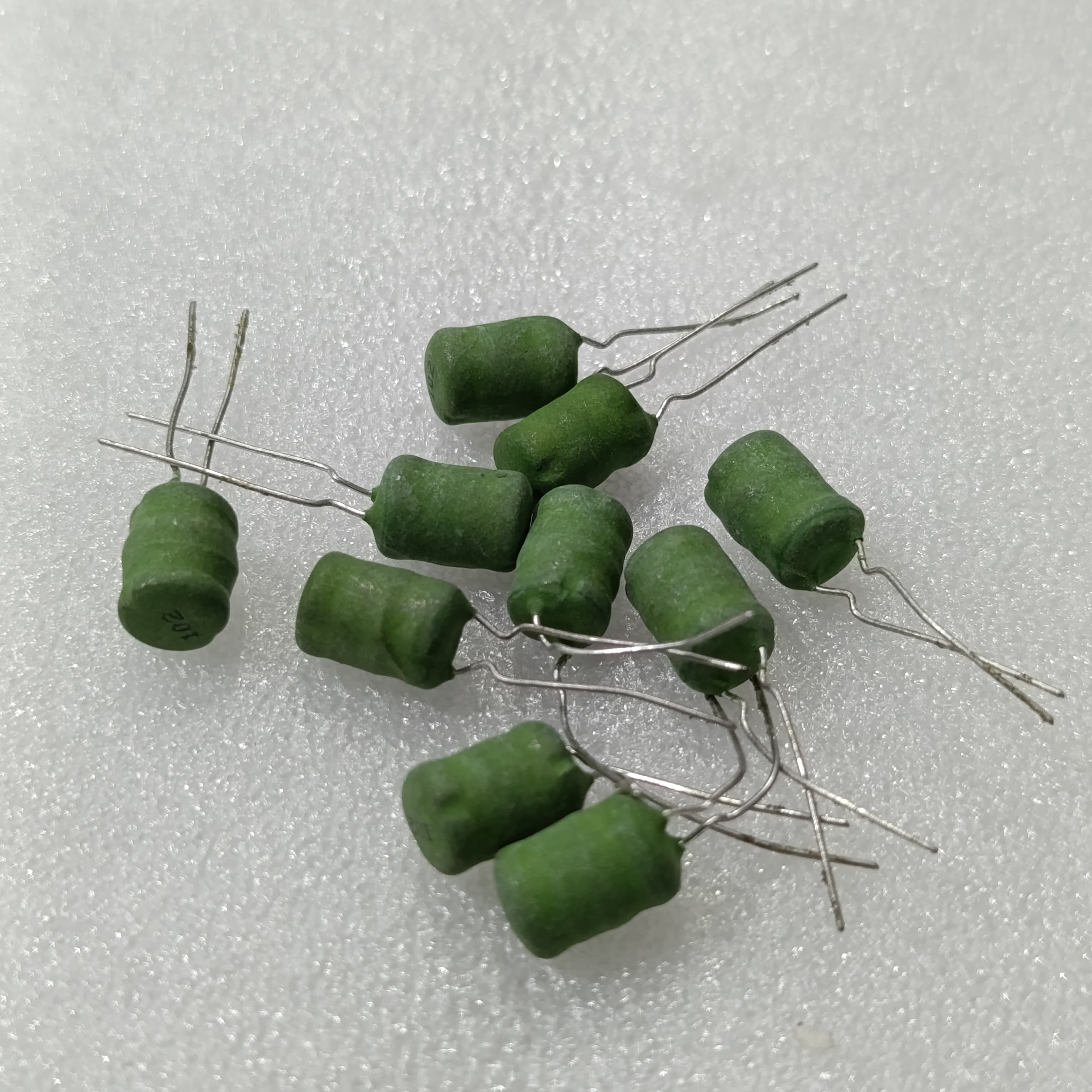 1mH Power Inductor ±10% 0.2A Radial - a group of small, green, cylindrical-shaped radial leaded inductors with the number 102 printed on one.