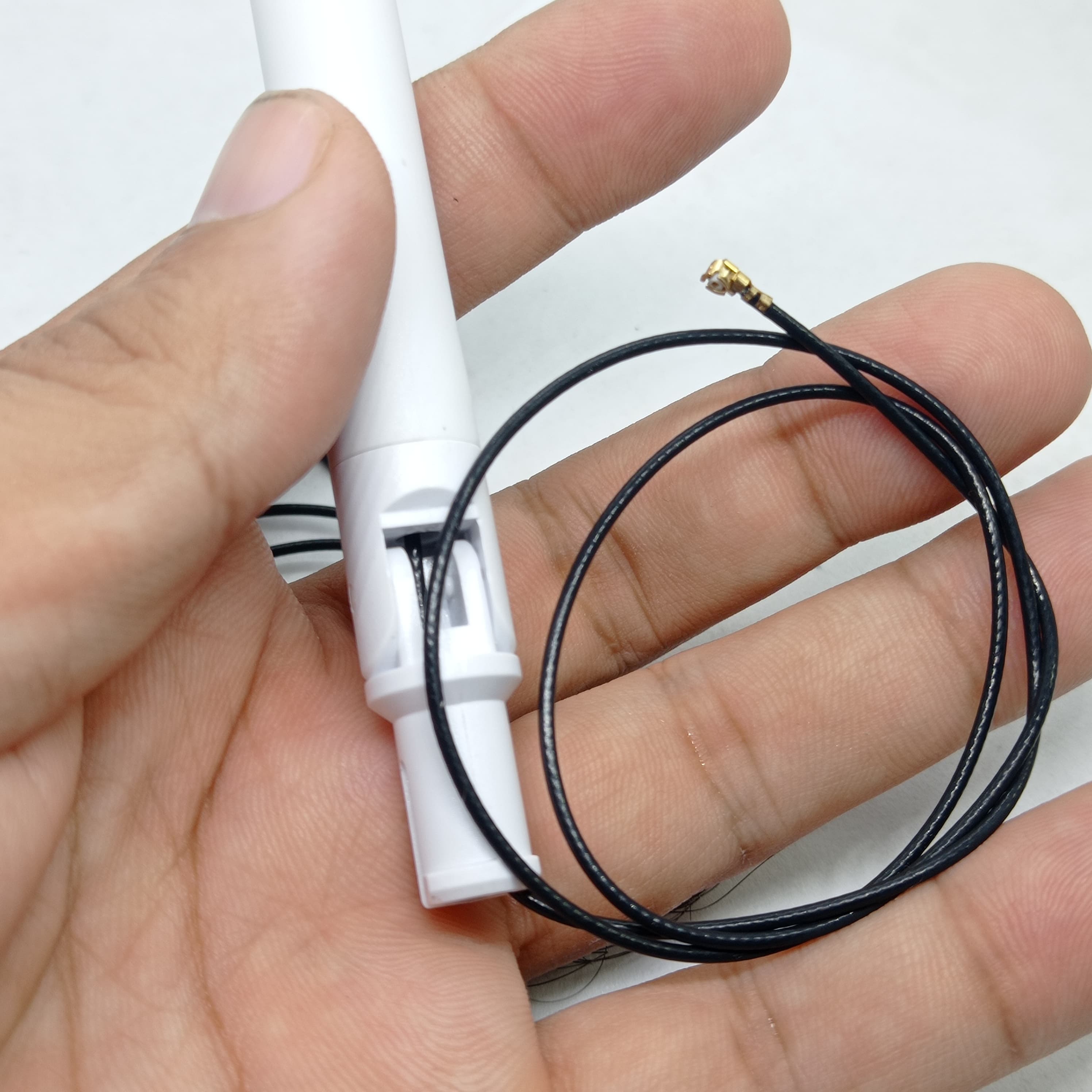 2.4GHz-5.8GHz 5db Wi-Fi Antenna With Ipex Connector - a white antenna held in a hand with a black cable ending in a small gold-coloured connector.