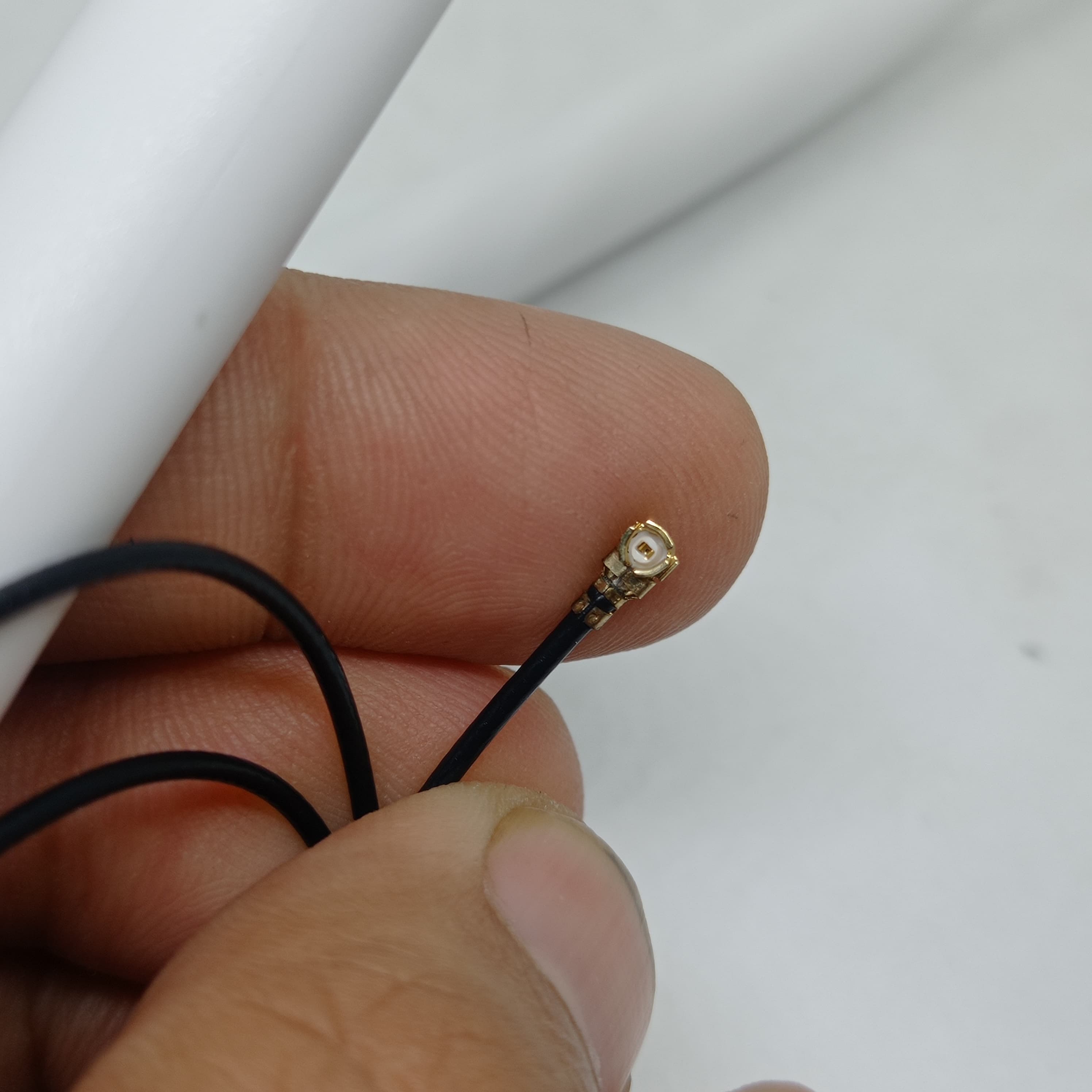 2.4GHz-5.8GHz 5db Wi-Fi Antenna With Ipex Connector - close-up of a hand holding the small gold-colored Ipex connector attached to a thin black cable.