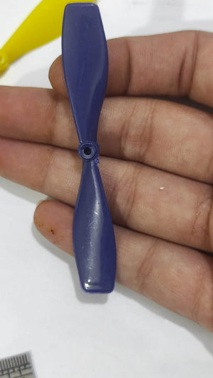 2 Vane Propellor For Small Toy Motor - a close-up shot of a blue two-blade plastic propeller held in a hand, with a yellow propeller partially visible.