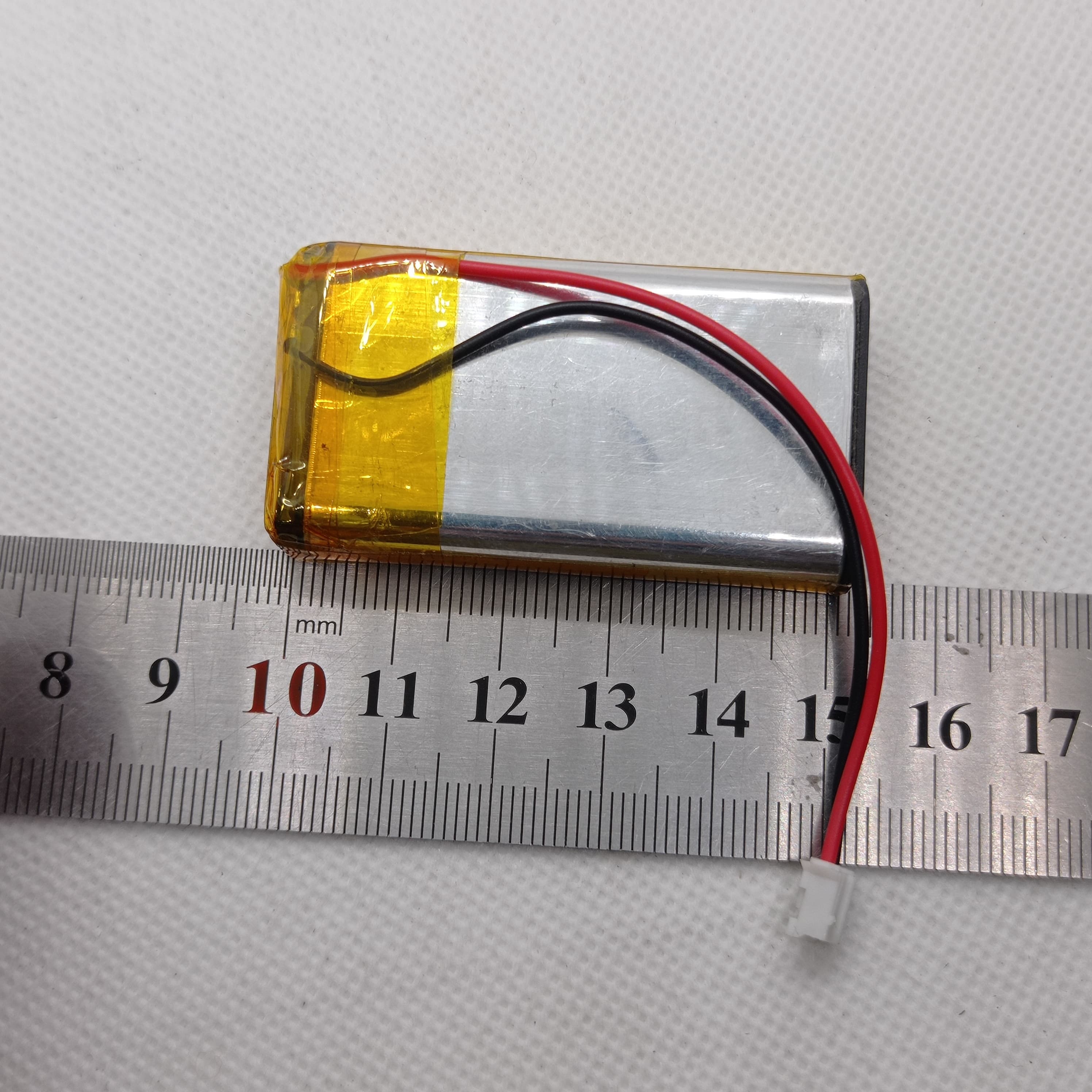2000mAh 3.7V Lithium-ion battery - shown as a rectangular silver cell with yellow tape, red and black wires, and a small white connector on a ruler.