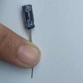 220 Uf 10V Through Hole Electrolytic Capacitor - a black cylindrical electronic component held by a finger, showing the printed 220uF 10V specifications.