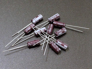 22uF 50V Electrolytic Capacitor - shown as a pile of small, brown, cylindrical radial lead components with white markings on a dark surface.