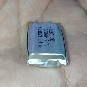 23mm x 28mm x 10mm 3.7V 740mA Li Ion Battery - a small rectangular silver-colored lithium polymer cell held in a palm, showing printed text including model PE801833.