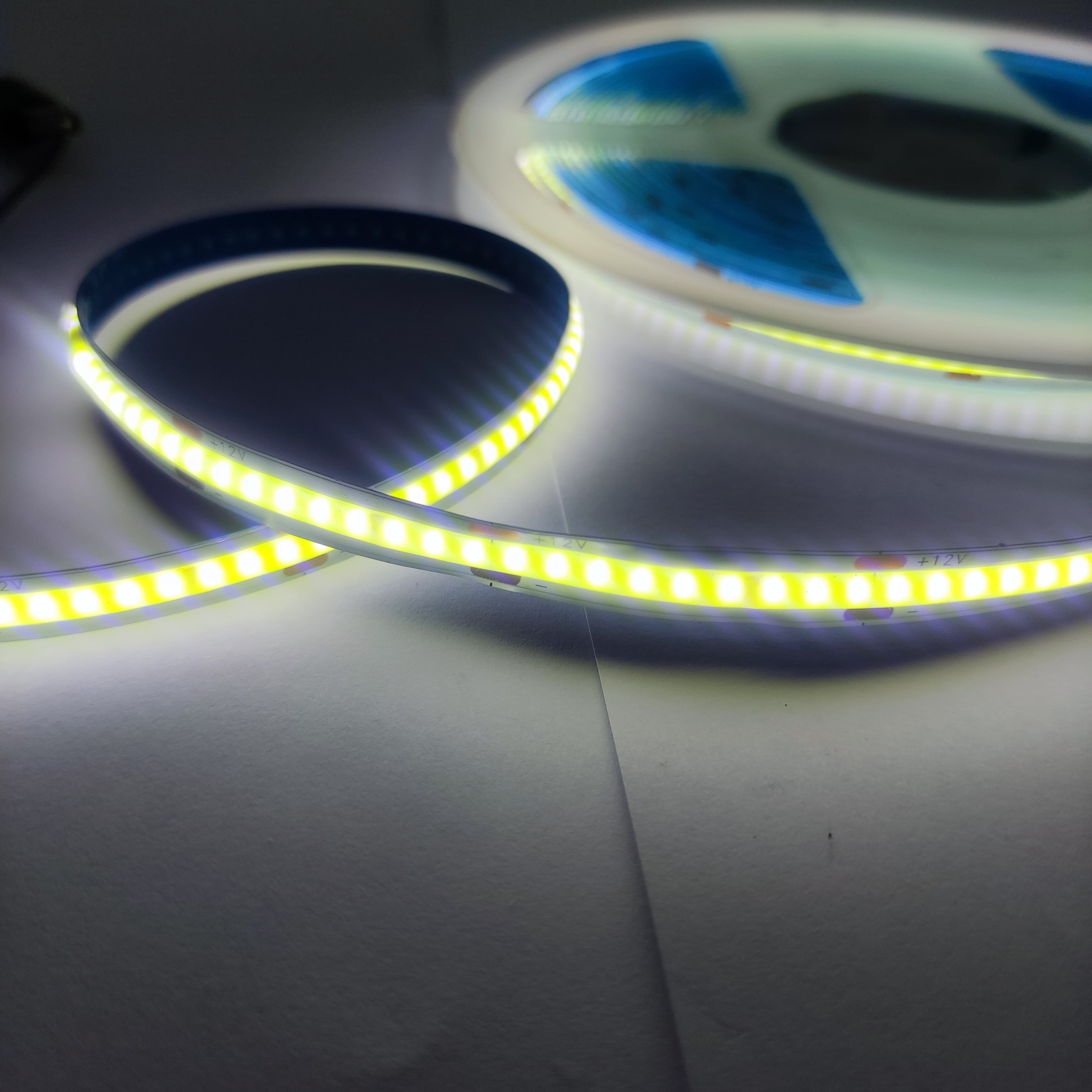 24V Warm White COB Car LED Light Strip For Car Decoration - shown as a glowing, flexible illuminated strip coiled on a reel with visible "+12V" markings.