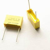 275V Capacitor 104k 0.1uF - shown as two yellow rectangular film capacitors with two metal leads each, featuring printed text including 0.1µF and 275VAC.