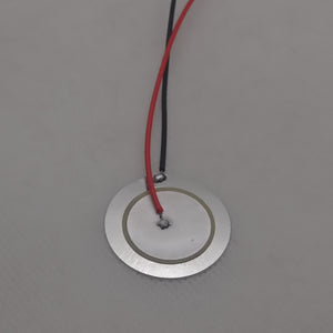 27mm Piezoelectric Ceramic Disc Piezo Element Plate With Wires - a circular silver metal disc with a ceramic center and attached red and black wires.