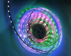 2812 LED Strip - coiled on a plastic spool, glowing with multi-coloured light against a blue textured background.