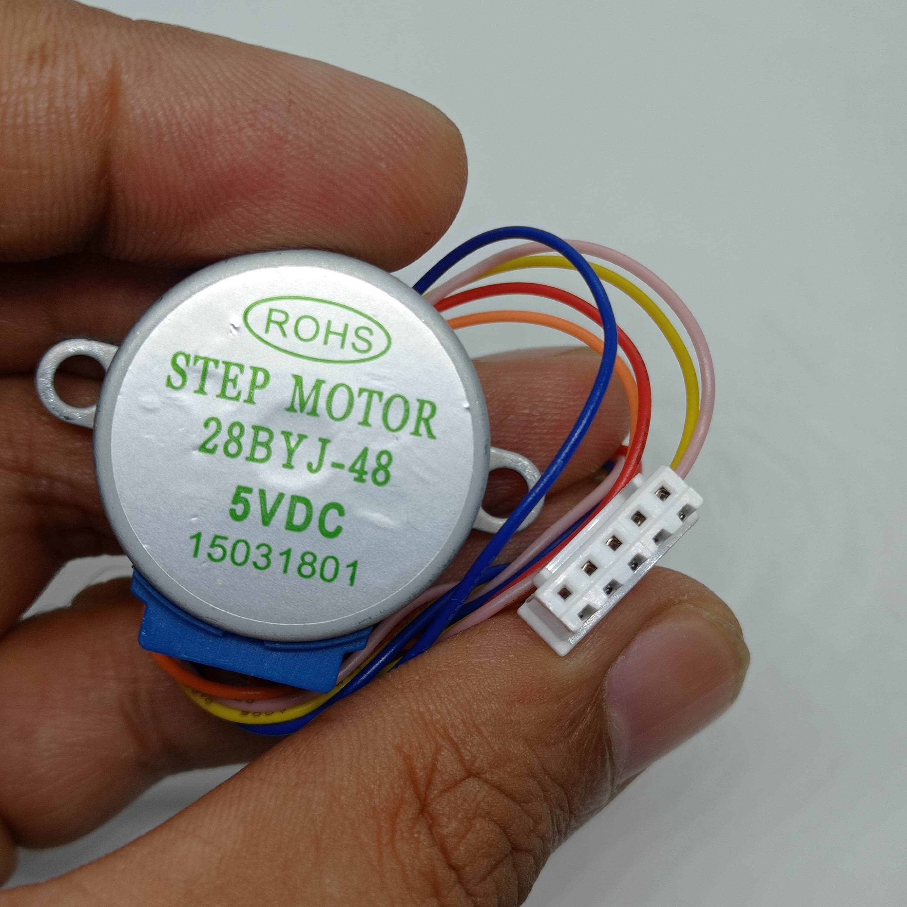 28BYJ-48 5V Stepper Motor - The Best Stepper Motor For Your Projects - held in a hand, showing the circular silver motor body with label text and a white five-pin connector attached by multi-coloured wires.