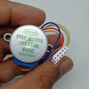 28BYJ-48 5V Stepper Motor - The Best Stepper Motor For Your Projects - held in a hand, showing the circular silver motor body with label text and a white five-pin connector attached by multi-coloured wires.