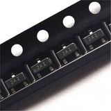 2N3906 MMBT3906 Transistor PNP SMD Sot-23 - shown in a close-up view of multiple black components arranged in a plastic carrier tape.