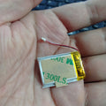 3.7V 100mAh Lithium-ion Polymer Battery - High Energy, Compact Power Source - a small rectangular silver battery with a yellow adhesive backing and a two-wire connector, held in a palm.