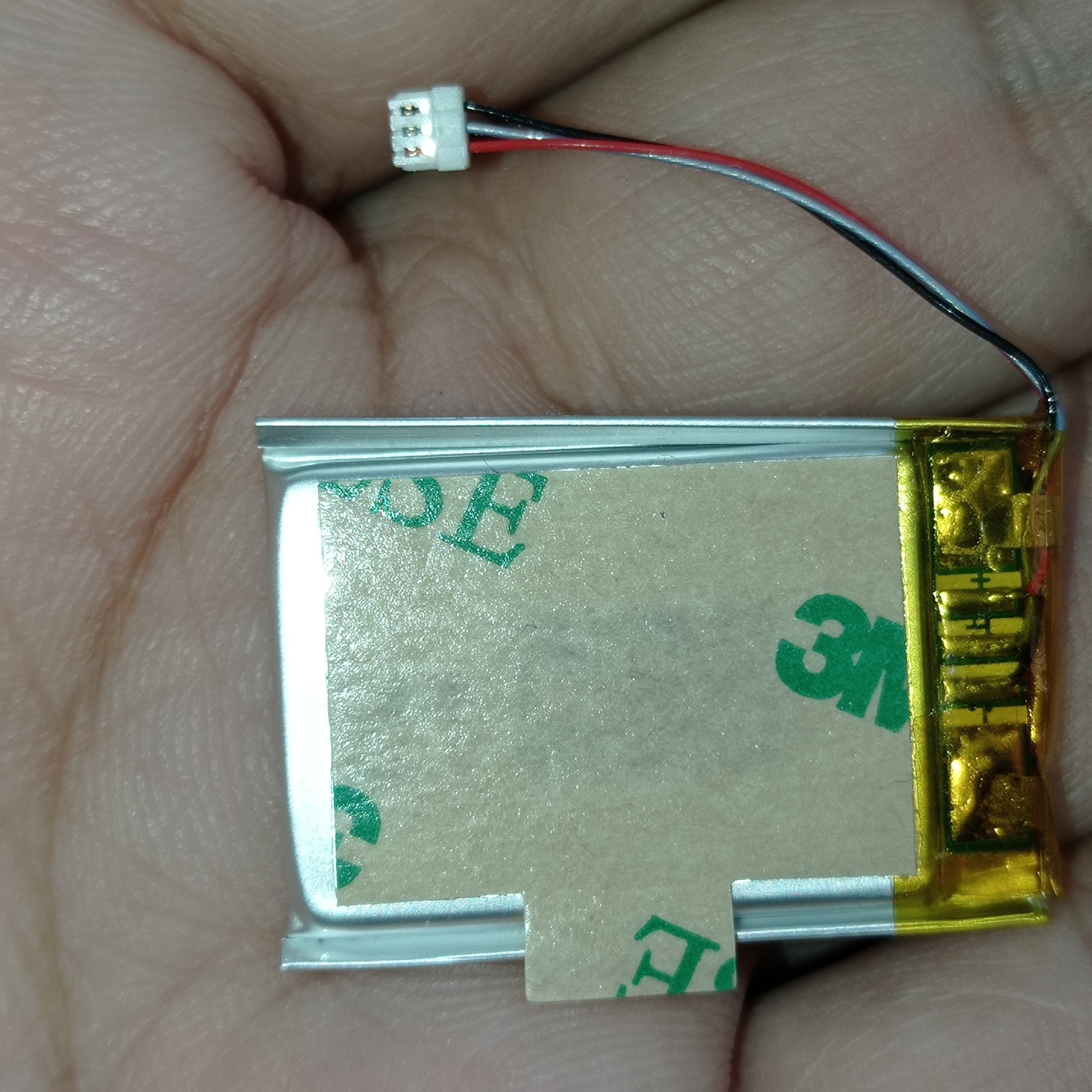 3.7V 100mAh Lithium-ion Polymer Battery - High Energy, Compact Power Source - a rectangular silver battery with a 3M adhesive backing and a three-pin white connector on a thin wire.