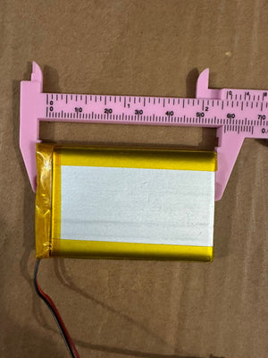 3.7V 2500mAh Lithium-Ion Rechargeable Battery - Li-Po Battery Pack - a rectangular gold-wrapped battery with two wires being measured by a pink plastic vernier caliper.