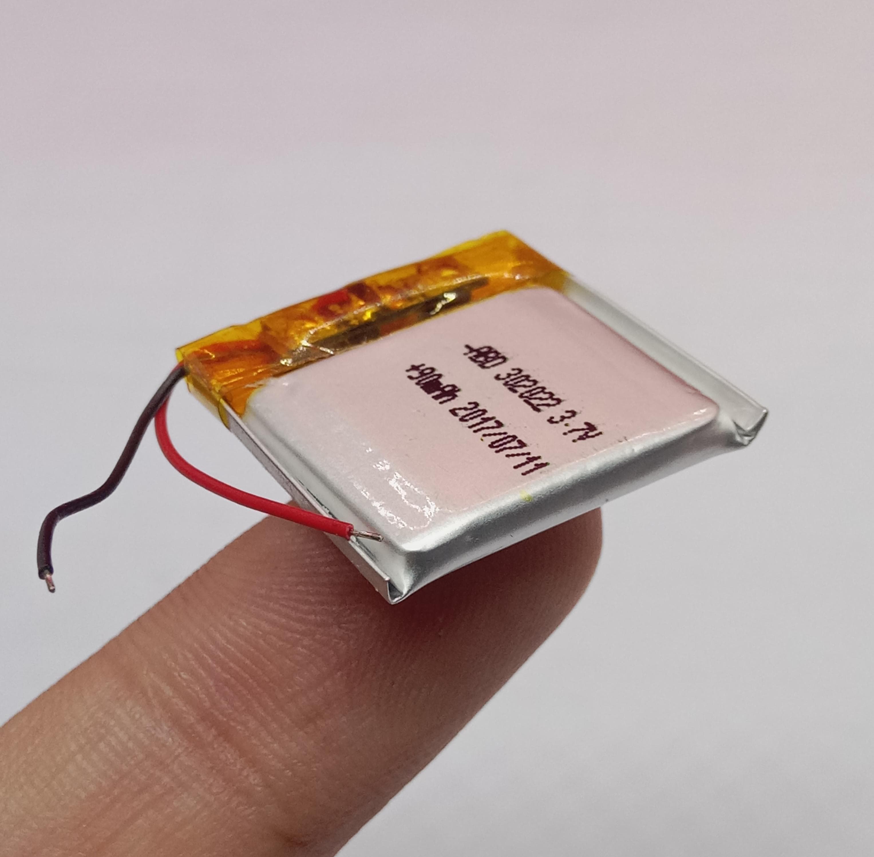 3.7V 90mAh Lithium Ion Li-ion Battery - a small silver rectangular cell with red and black wires and printed technical text.